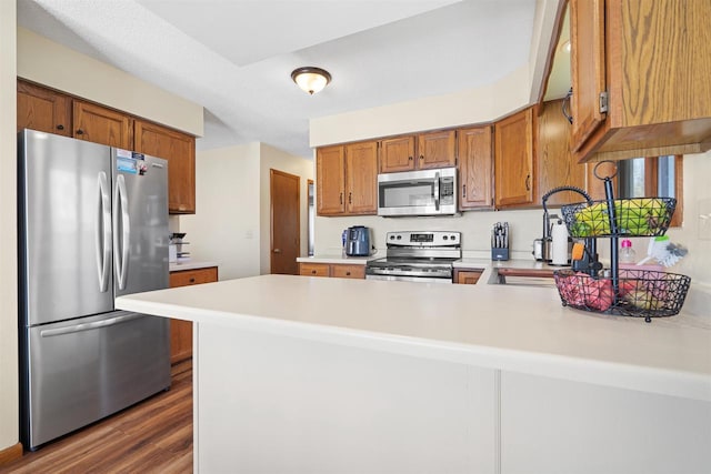 840 Waterworks Rd, Nekoosa, WI 54457 - kitchen featuring stainless steel appliances, light countertops, a peninsula, brown cabinetry, and dark wood finished floors