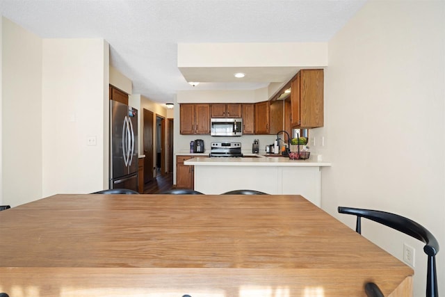 840 Waterworks Rd, Nekoosa, WI 54457 - kitchen with appliances with stainless steel finishes, a peninsula, brown cabinetry, a sink, and light countertops