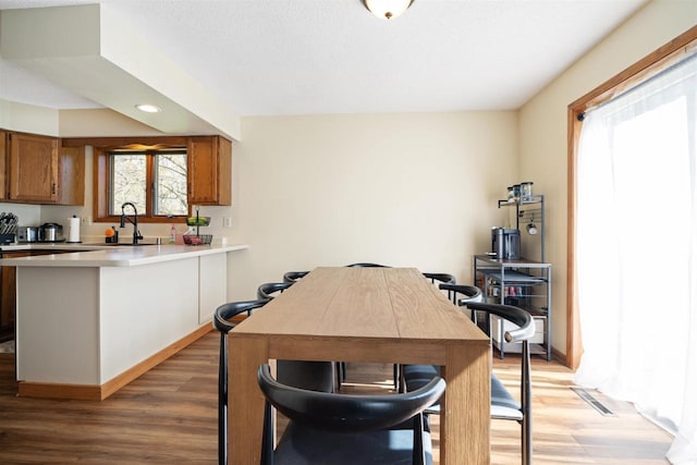 840 Waterworks Rd, Nekoosa, WI 54457 - kitchen with a sink, brown cabinets, a peninsula, light wood-style floors, and recessed lighting
