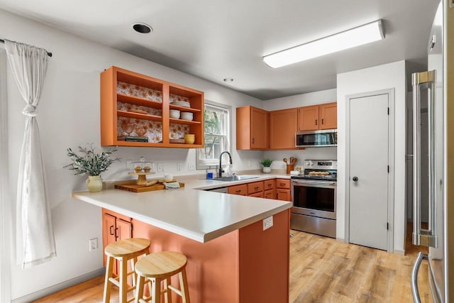 26 Prentice Pl, Madison, WI 53704 - kitchen featuring stainless steel appliances, a sink, a peninsula, a kitchen bar, and light wood-type flooring