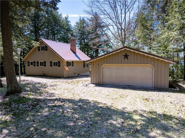 47025 Twin Pines Ln, Cable, WI 54821 - view of side of home featuring a chimney, an outdoor structure, metal roof, a detached garage, and board and batten siding