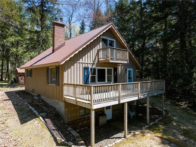 47025 Twin Pines Ln, Cable, WI 54821 - rear view of house featuring a balcony, metal roof, a chimney, a deck, and board and batten siding
