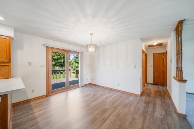 unfurnished dining area with wood finished floors, baseboards, and a chandelier