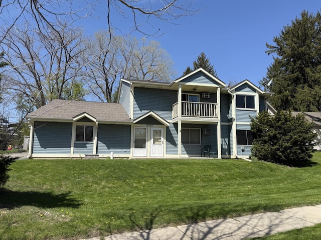 rear view of house featuring a balcony and a lawn
