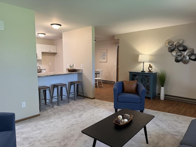 living area featuring baseboard heating, baseboards, and wood finished floors