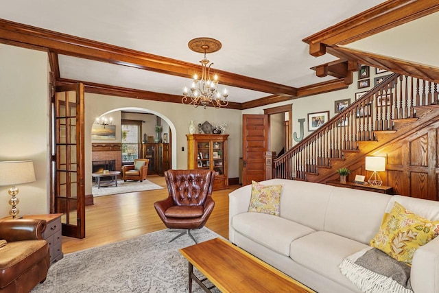 350 Madison St, Wisconsin Rapids, WI 54494 - living room featuring arched walkways, wood finished floors, a chandelier, a brick fireplace, and beam ceiling