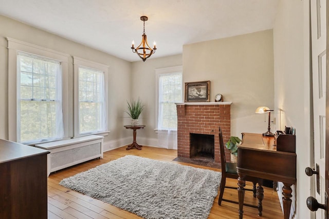 350 Madison St, Wisconsin Rapids, WI 54494 - living area featuring a brick fireplace, a chandelier, light wood-style flooring, and baseboards