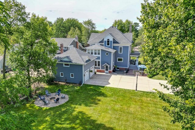 350 Madison St, Wisconsin Rapids, WI 54494 - rear view of property featuring a garage, an outdoor fire pit, a yard, a chimney, and concrete driveway