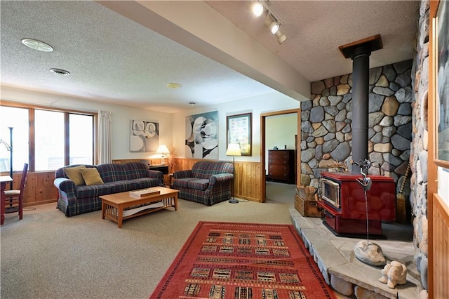 23075 Missionary Point Dr, Cable, WI 54821 - carpeted living room featuring a wood stove, a textured ceiling, wainscoting, and wood walls