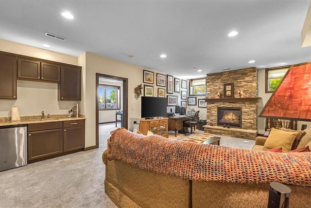 335 Bella Way, Sun Prairie, WI 53590 - living area featuring bar with sink, a stone fireplace, light carpet, and recessed lighting