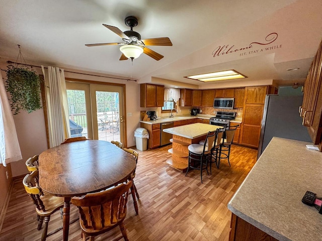 N9960 Meadowlark Ln, Crivitz, WI 54114 - kitchen with stainless steel appliances, brown cabinetry, a center island, light countertops, and light wood-style floors