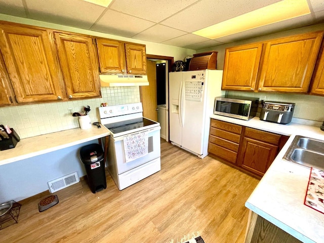 108 S Center St, Orfordville, WI 53576 - kitchen with white appliances, under cabinet range hood, a drop ceiling, brown cabinetry, and light countertops