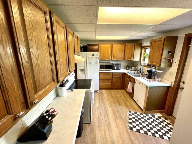 108 S Center St, Orfordville, WI 53576 - kitchen featuring white appliances, a sink, a drop ceiling, light wood finished floors, and brown cabinetry