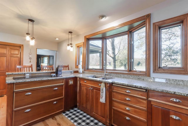 N4618 State Road 49, Waupaca, WI 54981 - kitchen with a sink, black electric stovetop, brown cabinets, decorative light fixtures, and light stone countertops