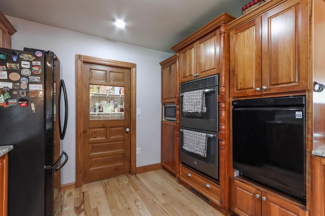 N4618 State Road 49, Waupaca, WI 54981 - kitchen featuring black appliances, light wood finished floors, brown cabinetry, light stone counters, and baseboards