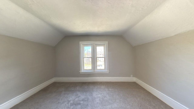 additional living space with vaulted ceiling, carpet, baseboards, and a textured ceiling