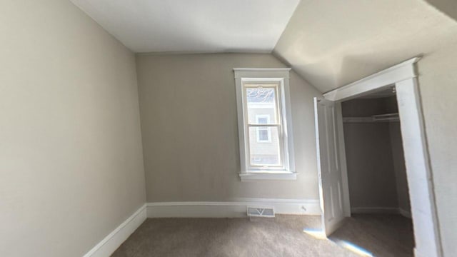 unfurnished bedroom featuring lofted ceiling, carpet floors, and baseboards