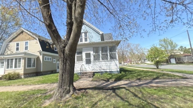 view of front of house with a sunroom, a front yard, a gambrel roof, and entry steps