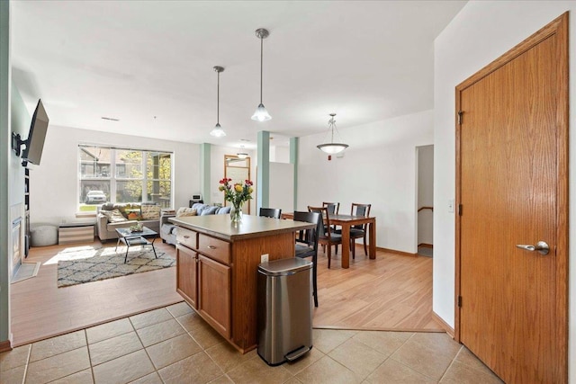 1119 Enterprise Dr, Verona, WI 53593 - kitchen with open floor plan, brown cabinetry, light tile patterned floors, pendant lighting, and a kitchen island