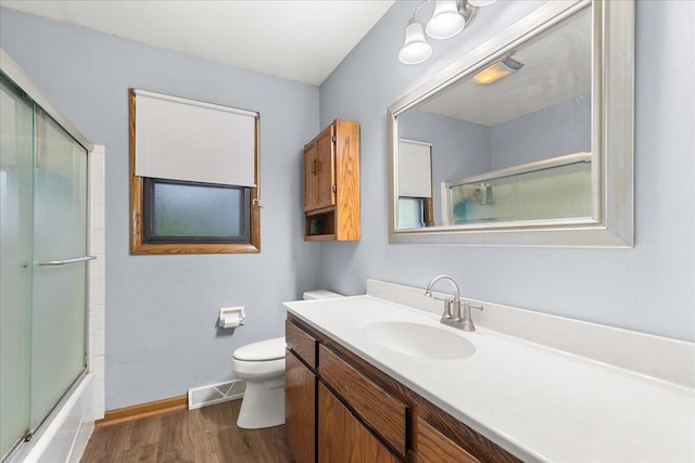 1528 Jefferson St, West Bend, WI 53090 - bathroom featuring wood finished floors, toilet, vanity, baseboards, and enclosed tub / shower combo