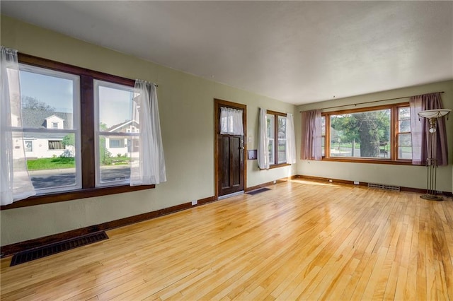 unfurnished living room featuring baseboards and light wood finished floors