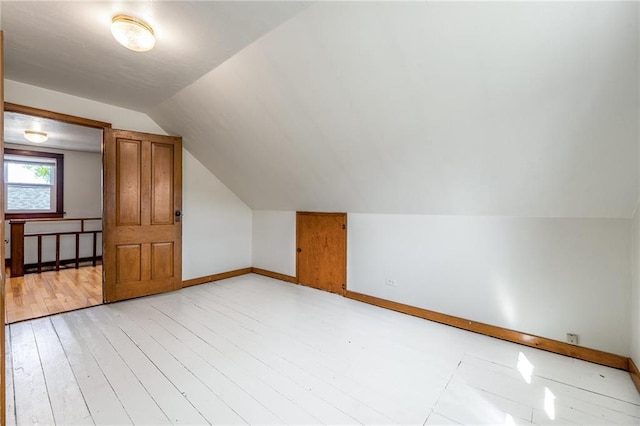 additional living space featuring vaulted ceiling, baseboards, and light wood finished floors
