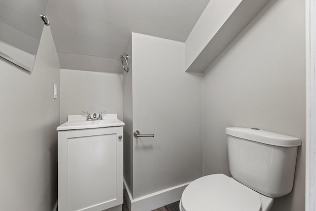 bathroom with toilet, vanity, and wood finished floors