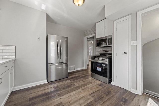 kitchen with appliances with stainless steel finishes, white cabinetry, dark wood-style floors, light countertops, and baseboards
