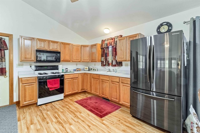 1809 S Badger Ct, Arkdale, WI 54613 - kitchen with freestanding refrigerator, gas range, black microwave, lofted ceiling, and light countertops