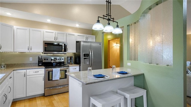 2649 W Menomonie St, Eau Claire, WI 54703 - kitchen featuring stainless steel appliances, white cabinetry, hanging light fixtures, a breakfast bar area, and light wood-style flooring
