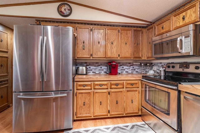 1870 County Road F Unit L69, Friendship, WI 53934 - kitchen featuring stainless steel appliances, lofted ceiling, light countertops, light wood finished floors, and a textured ceiling
