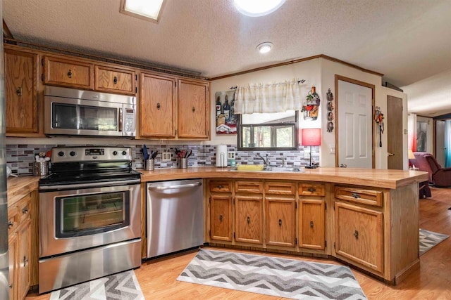 1870 County Road F Unit L69, Friendship, WI 53934 - kitchen featuring stainless steel appliances, a sink, tasteful backsplash, light wood-style floors, and a textured ceiling