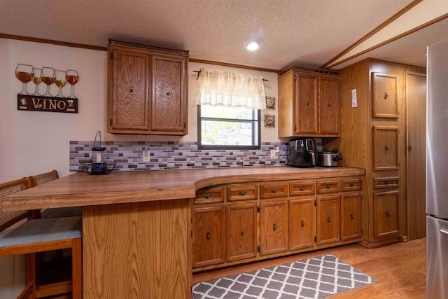 1870 County Road F Unit L69, Friendship, WI 53934 - kitchen featuring a textured ceiling, brown cabinets, decorative backsplash, and ornamental molding