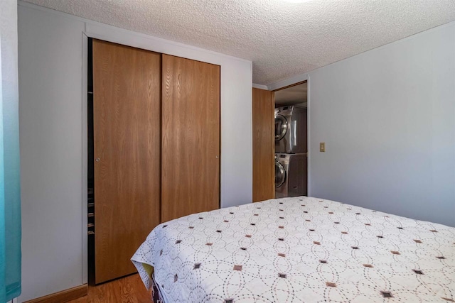 1870 County Road F Unit L69, Friendship, WI 53934 - bedroom featuring stacked washer and clothes dryer, a textured ceiling, a closet, and wood finished floors