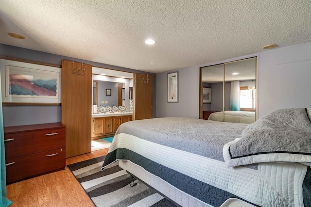 1870 County Road F Unit L69, Friendship, WI 53934 - bedroom with wood finished floors, a textured ceiling, a closet, ensuite bath, and recessed lighting