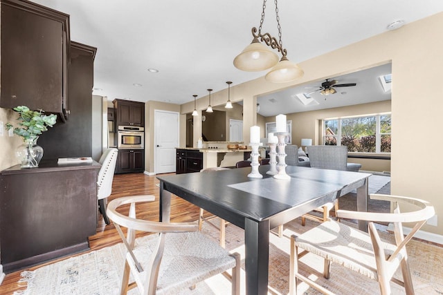 252 Willow Dr, Hartland, WI 53029 - dining room featuring light wood-style flooring, a ceiling fan, and baseboards