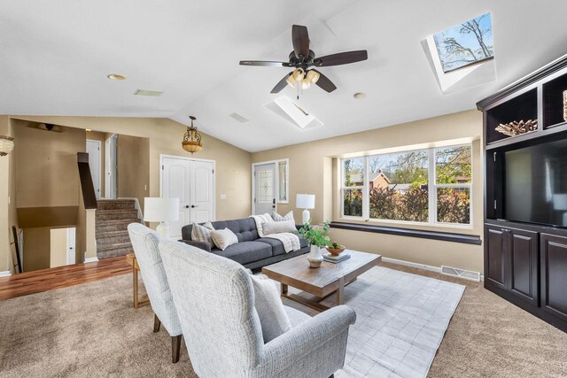 252 Willow Dr, Hartland, WI 53029 - carpeted living room featuring a skylight, vaulted ceiling, stairs, ceiling fan, and baseboards