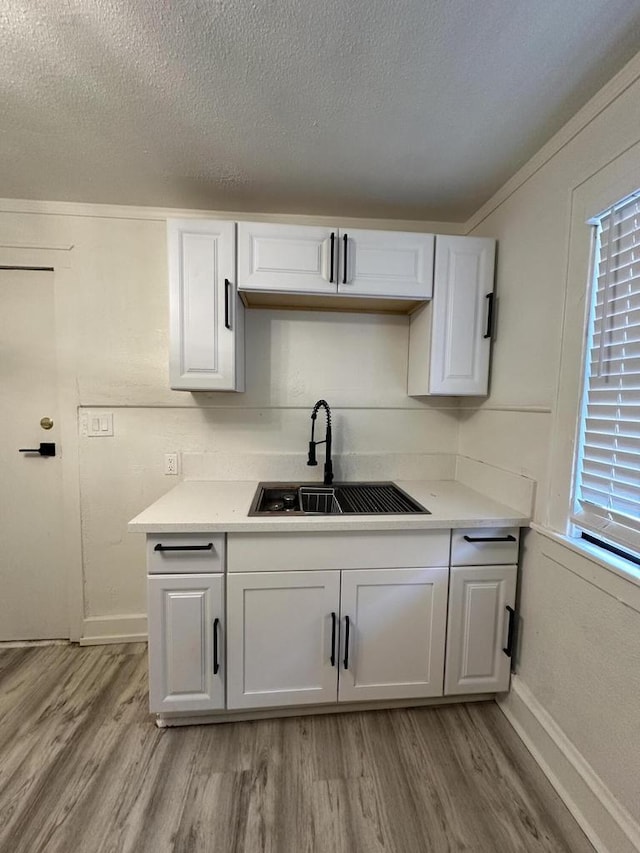 3158 N 39th St Unit 3160, Milwaukee, WI 53216 - kitchen with a sink, light wood-style floors, white cabinets, light countertops, and a textured ceiling