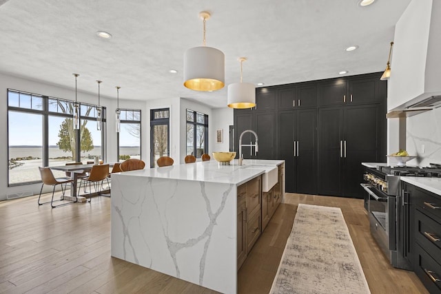 536 Sunrise Bay Rd, Neenah, WI 54956 - kitchen with stainless steel range, wall chimney range hood, a sink, recessed lighting, and dark cabinets