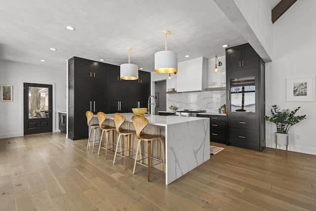 536 Sunrise Bay Rd, Neenah, WI 54956 - kitchen featuring dark cabinets, recessed lighting, a breakfast bar, backsplash, and light wood finished floors