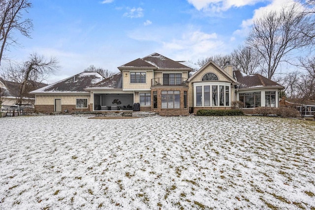 536 Sunrise Bay Rd, Neenah, WI 54956 - snow covered back of property with a chimney, brick siding, a sunroom, and a patio area