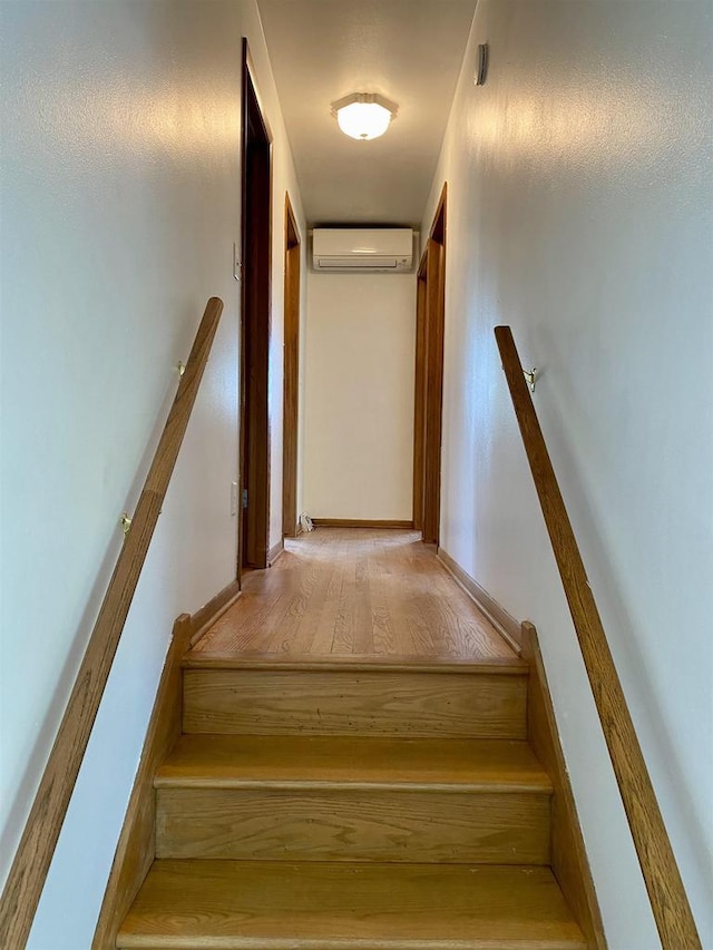 stairs featuring a wall unit AC and wood finished floors