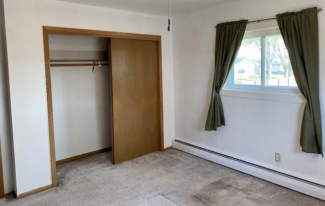 unfurnished bedroom with a baseboard heating unit, light carpet, and a closet