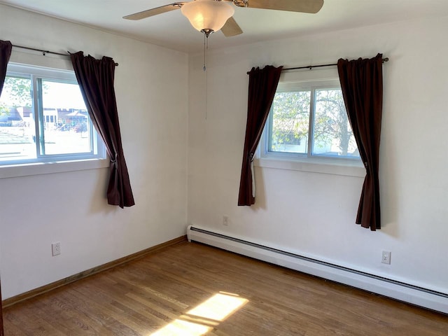 empty room featuring a baseboard radiator, wood finished floors, a ceiling fan, and baseboards