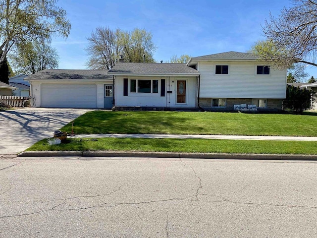 tri-level home featuring an attached garage, concrete driveway, a front yard, and a chimney