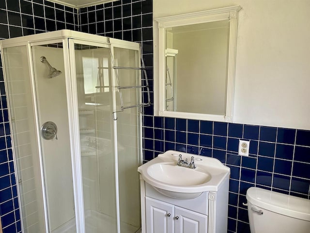bathroom featuring tile walls, a stall shower, toilet, and vanity