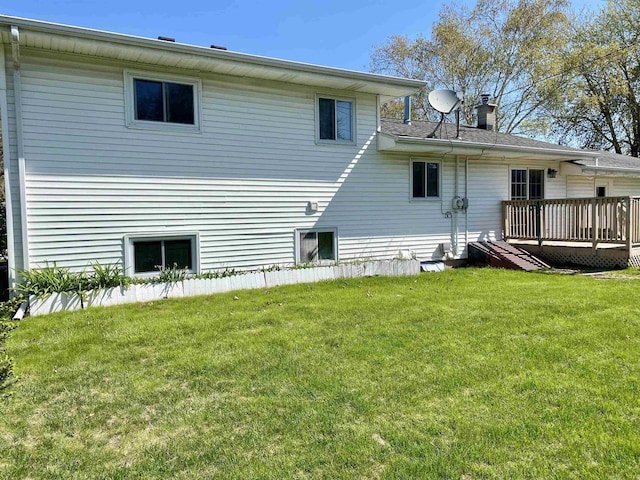 back of property with a wooden deck, a lawn, and a chimney