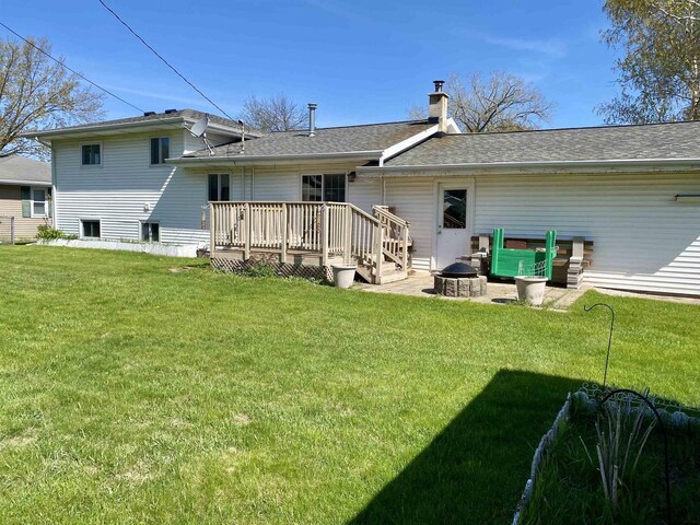 rear view of house featuring a wooden deck, a yard, a chimney, and a fire pit