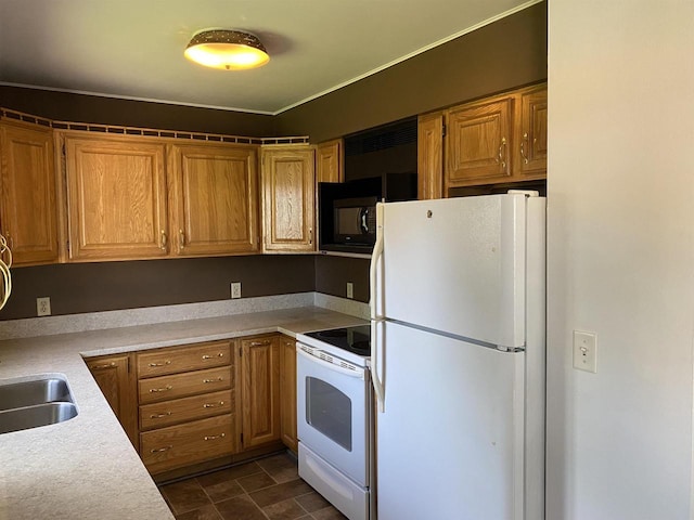 kitchen with white appliances, light countertops, a sink, and brown cabinetry