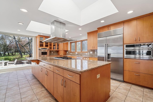 7515 N Beach Dr, Fox Point, WI 53217 - kitchen with appliances with stainless steel finishes, a skylight, island exhaust hood, a kitchen island, and light tile patterned flooring